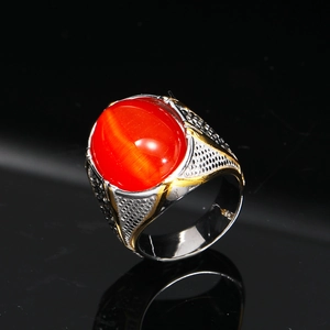 Dettaglio macro di anello vintage da uomo con gemma rossa e fascia testurizzata