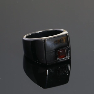 Primer plano de anillo para hombre en titanio negro mate con piedra roja cuadrada