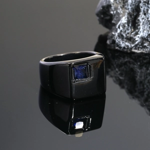 Detalle macro de anillo de titanio negro para hombre con piedra azul cuadrada sobre roca