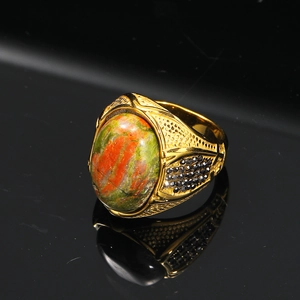Macro di un anello vintage dorato con pietra preziosa verde-rossa e pietre nere