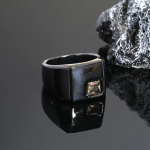 Detalle macro de un anillo negro para hombre en titanio cepillado con gema ámbar cuadrada