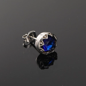 Détail macro d'une boucle d'oreille en pierre bleue ronde avec support en acier titane