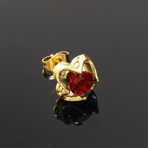 Vue macro détaillée d'une boucle d'oreille cœur vintage en or avec zircon rouge au centre