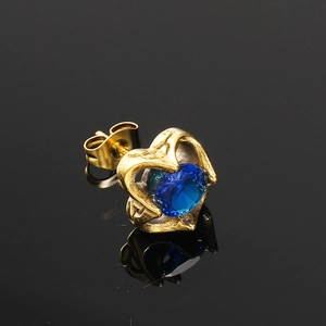 Vue macro d'une boucle d'oreille cœur dorée avec zircon bleu sur fond noir poli