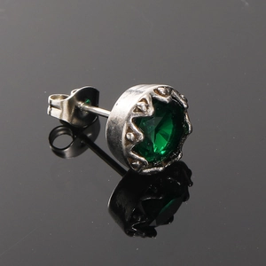 Gros plan d'une boucle d'oreille en pierre verte avec monture couronne argentée et fermoir papillon