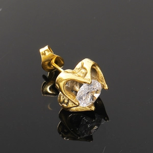 Gros plan d'une boucle d'oreille cœur doré avec cristal clair et reflet sur noir