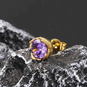 Macro detail of a purple crystal stud earring with gold-plated claw setting on dark rock