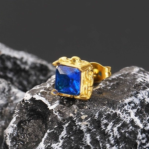 Makro-Detail des quadratischen blauen Zirkon-Ohrrings mit goldener Gravur auf Stein