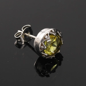 Gros plan sur un clou d'oreille en zircon jaune avec monture couronne sur fond noir