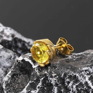 Macro shot of single gold-plated stud earring with yellow faceted gemstone on black stone