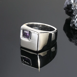 Detalle macro de un anillo cuadrado de acero plateado con gema púrpura en espejo negro