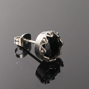 Vue macro d'un clou d'oreille en gemme noire avec sertissage couronne en acier argenté