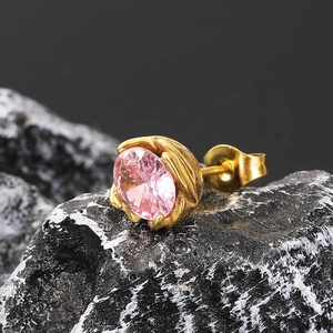 Close-up of pink zircon stud earring with golden textured base on a rocky background