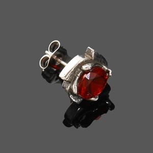 Vue détaillée d'un clou d'oreille argenté vintage avec un zircon rouge foncé griffé