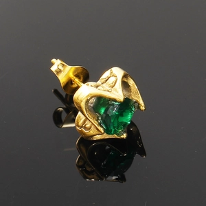 Vue macro d'une boucle d'oreille cœur en or avec pierre précieuse cœur vert émeraude