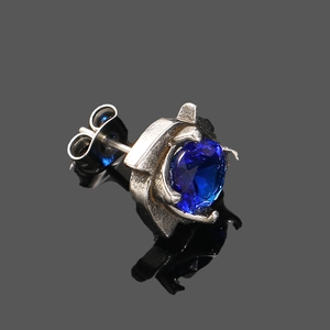 Vue macro d'une boucle d'oreille en zircon bleu foncé avec monture à griffes argentée