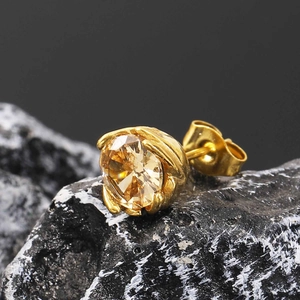 Detail view of gold stud earring with champagne stone on a natural black stone texture