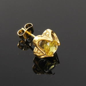 Gros plan d'un clou d'oreille en cristal champagne avec serti à quatre griffes dorées