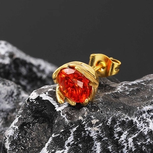 Detailed close-up of an orange faceted gemstone earring with gold leaf-shaped setting
