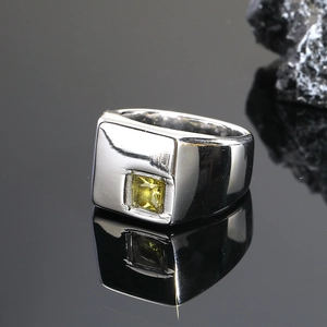 Detalle de anillo cuadrado plateado para hombre con una gema amarilla central de corte cuadrado