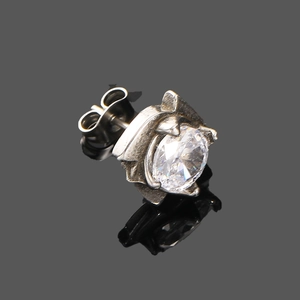 Détail d'une boucle d'oreille punk en acier inoxydable avec zircone sur miroir noir brillant