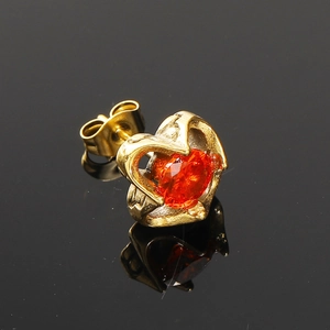 Vue macro d'une boucle d'oreille cœur dorée avec pierre ovale rouge-orange et fermoir papillon