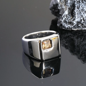 Vista macro de un anillo cuadrado de acero pulido con una gema amarilla engastada