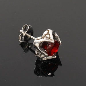Détail macro d'un clou d'oreille cœur rétro avec pierre rouge et métal argenté vieilli