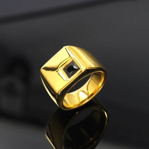 Vista macro lateral de un anillo cuadrado bañado en oro con una gema negra central y bordes