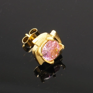Gros plan d'une puce d'oreille dorée avec un zircon rose serti dans une monture à quatre griffes