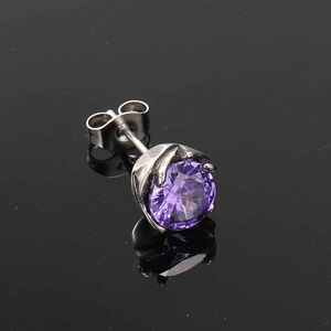 Macro shot of purple round cut crystal stud earring with silver prong setting on black mirror