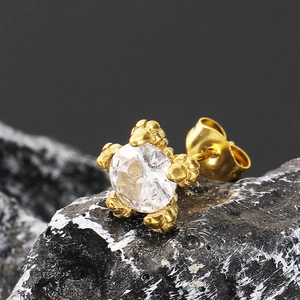 Makroaufnahme eines Drachenkrallen-Ohrsteckers mit Zirkonia-Stein und Gold-Finish auf Stein