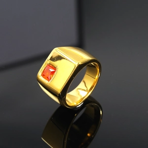 Vista macro del anillo de sello dorado con superficie pulida y gema roja incrustada