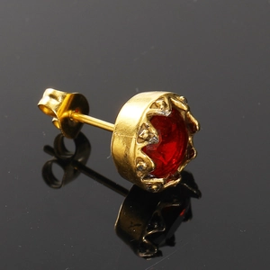 Vue macro de la boucle d'oreille en acier doré avec zircon rouge serti en couronne