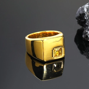 Primer plano de anillo cuadrado dorado con superficie de metal cepillado y pequeño circón