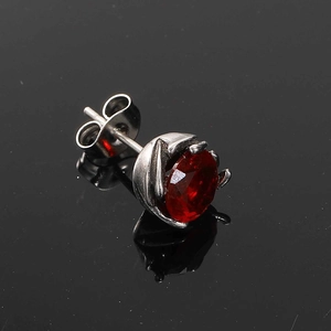 Macro side view of silver titanium steel stud earring with oval red gemstone inlay
