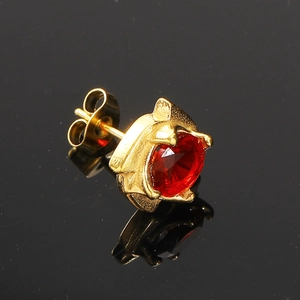 Vue macro d'une boucle d'oreille en zircon rouge avec monture dorée à quatre griffes et poussoir