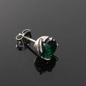 Macro detail of vintage titanium steel stud earring with green gemstone and claw setting