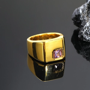 Detalle de anillo de sello cuadrado dorado con acabado cepillado y gema púrpura