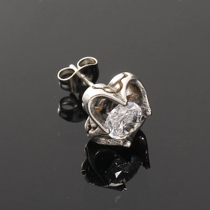 Détail d'une boucle d'oreille cœur en acier titane avec zircone cubique étincelante sur fond noir