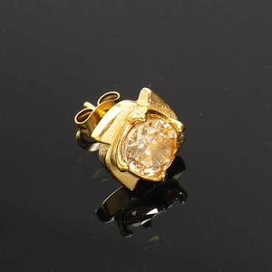 Vue macro d'une boucle d'oreille dorée avec zircon serti griffes et fermoir papillon