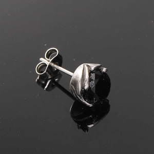 Macro shot of vintage titanium steel stud earring with a faceted black gemstone and leaf prongs