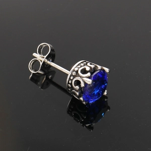 Gros plan d'un clou d'oreille en acier titane avec zircon bleu foncé et serti couronne vintage