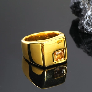 Detalle de anillo cuadrado dorado con circonita ámbar en superficie pulida