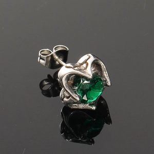 Macro d'une boucle d'oreille cœur en argent vintage avec gemme verte à facettes