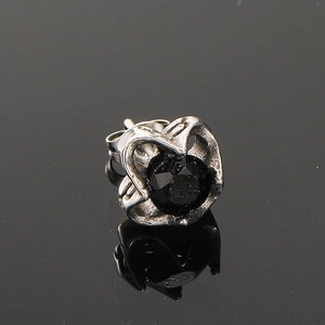 Vue macro d'un clou d'oreille en acier titane vintage avec une pierre noire ronde