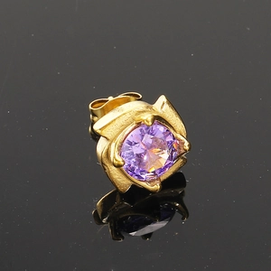 Vue macro d'un clou d'oreille doré avec un zircon violet serti de quatre griffes élégantes