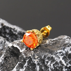 Détail d'une boucle d'oreille rétro en or avec zircon orange sur roche noire texturée