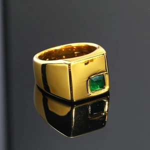 Primer plano de anillo de sello dorado con piedra verde cuadrada sobre fondo negro pulido
