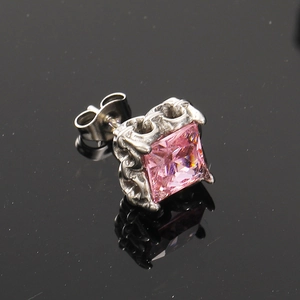 Vista macro di orecchino punk con zircone rosa quadrato e base in acciaio con incisioni